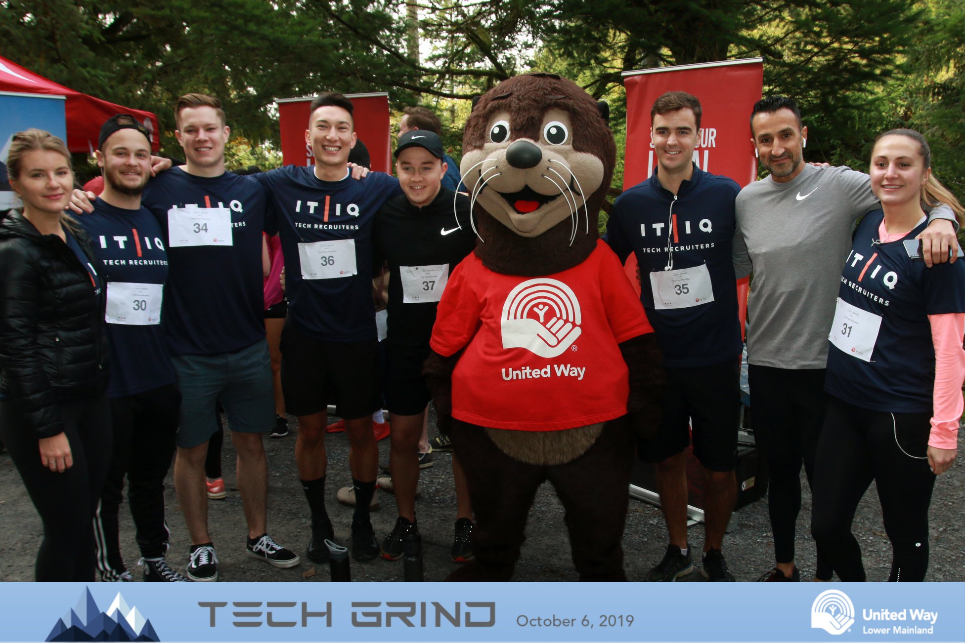 IT/IQ employee pose for a photo with otter mascot after the United Way Tech Grind 2019 trail run